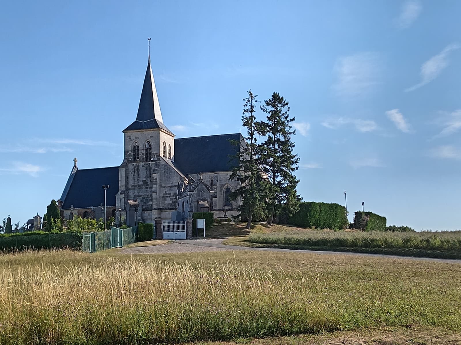 L'église de Saint-Sulpice (Oise) et son clocher pointu dominant le village depuis sa butte, entourée de son cimetière, lors d'une sortie du Vélo Club de Mouy en juillet 2026