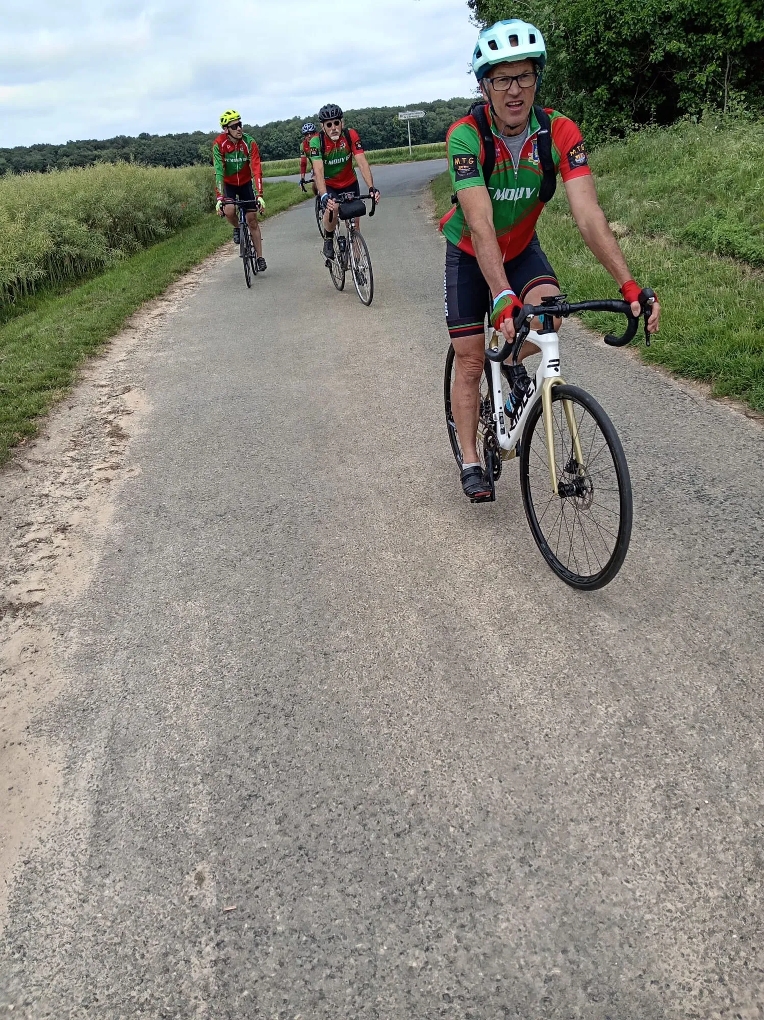 Quatre cyclistes du VC Mouy en maillot vert et rouge roulant sur une petite route de campagne lors de la rando de Le Meux