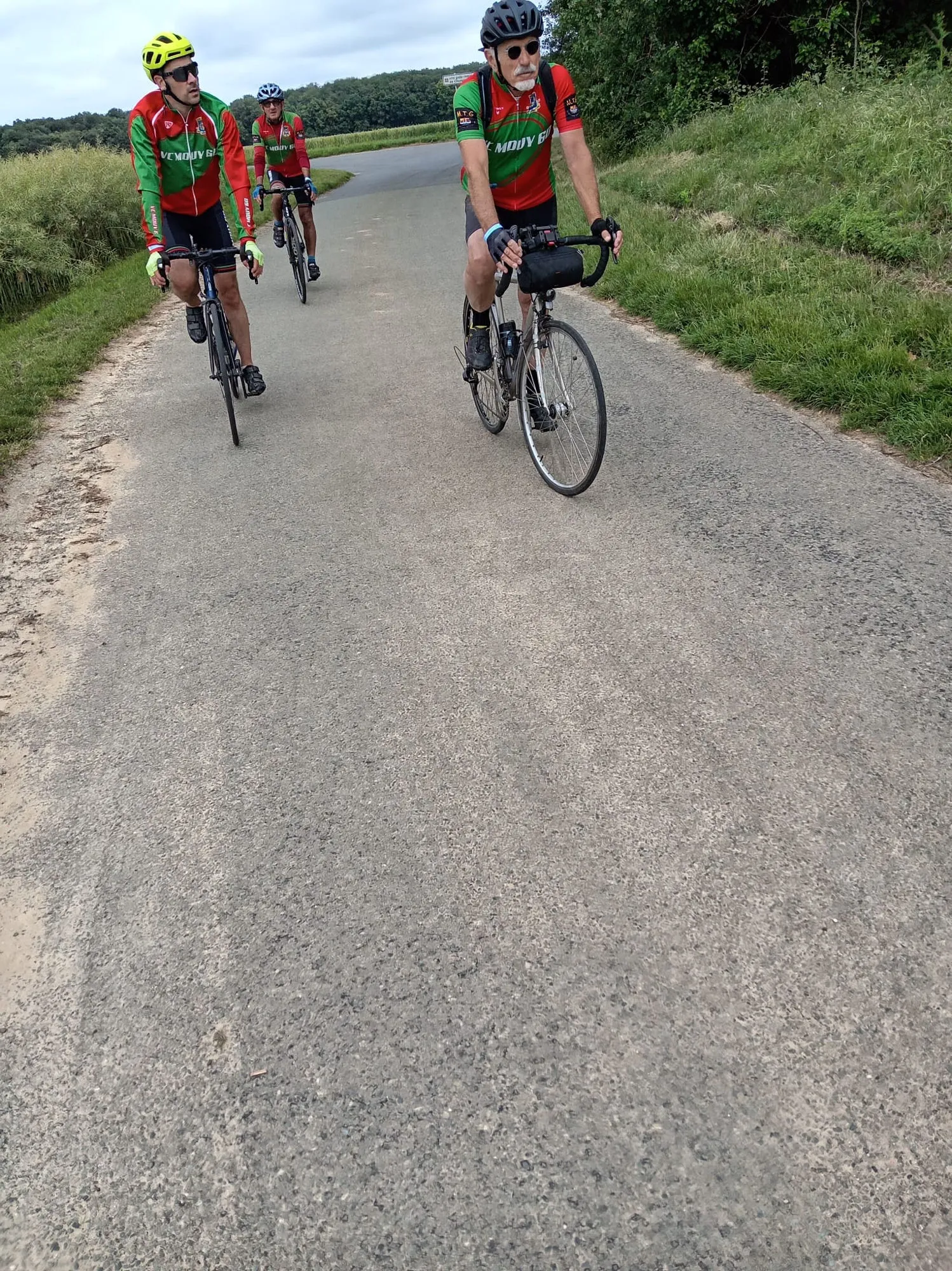 Trois cyclistes du VC Mouy en maillot vert et rouge à l'approche d'un bois sur le parcours de la rando de Le Meux