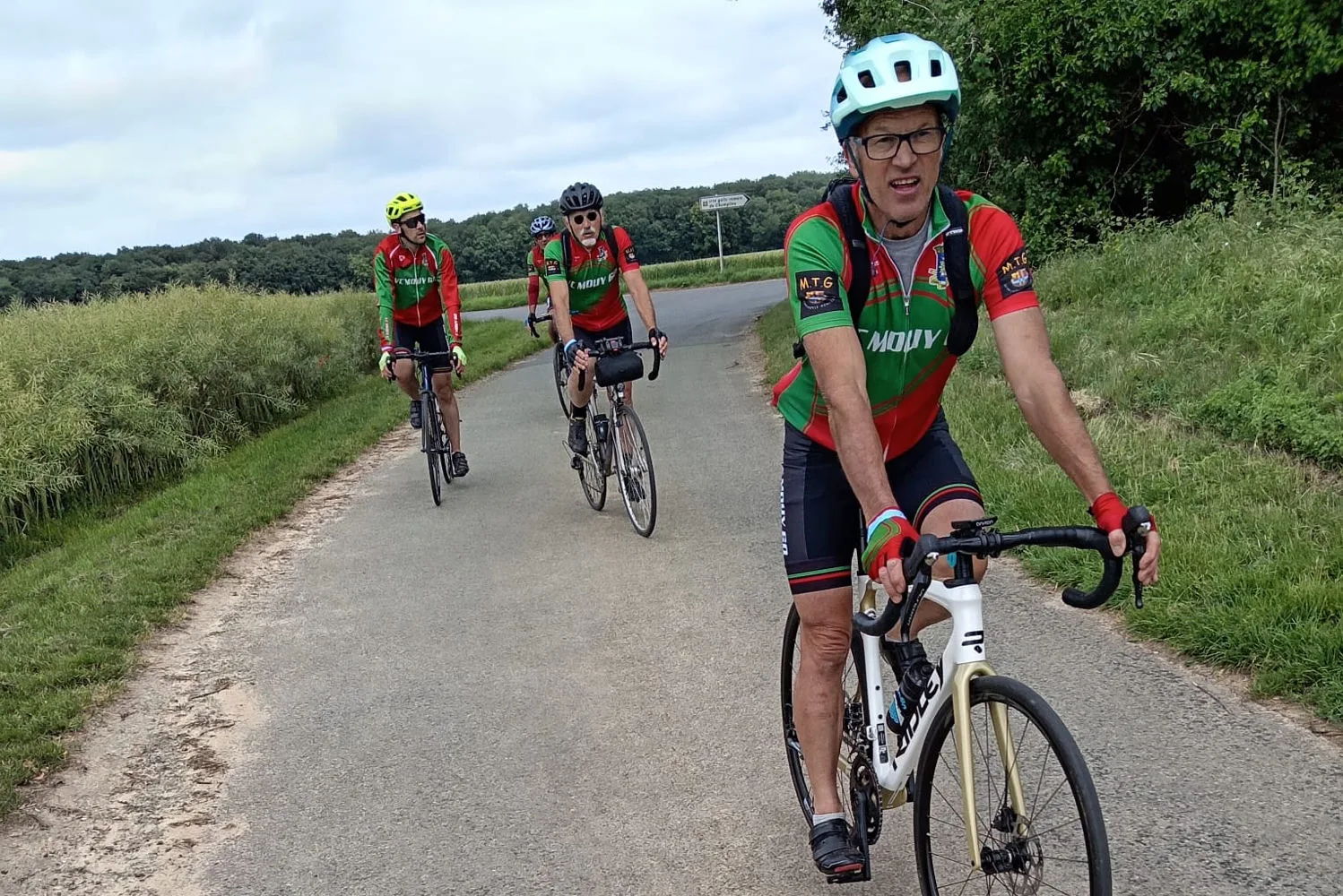 Quatre cyclistes du VC Mouy en maillot vert et rouge roulant sur une petite route de campagne lors de la rando de Le Meux
