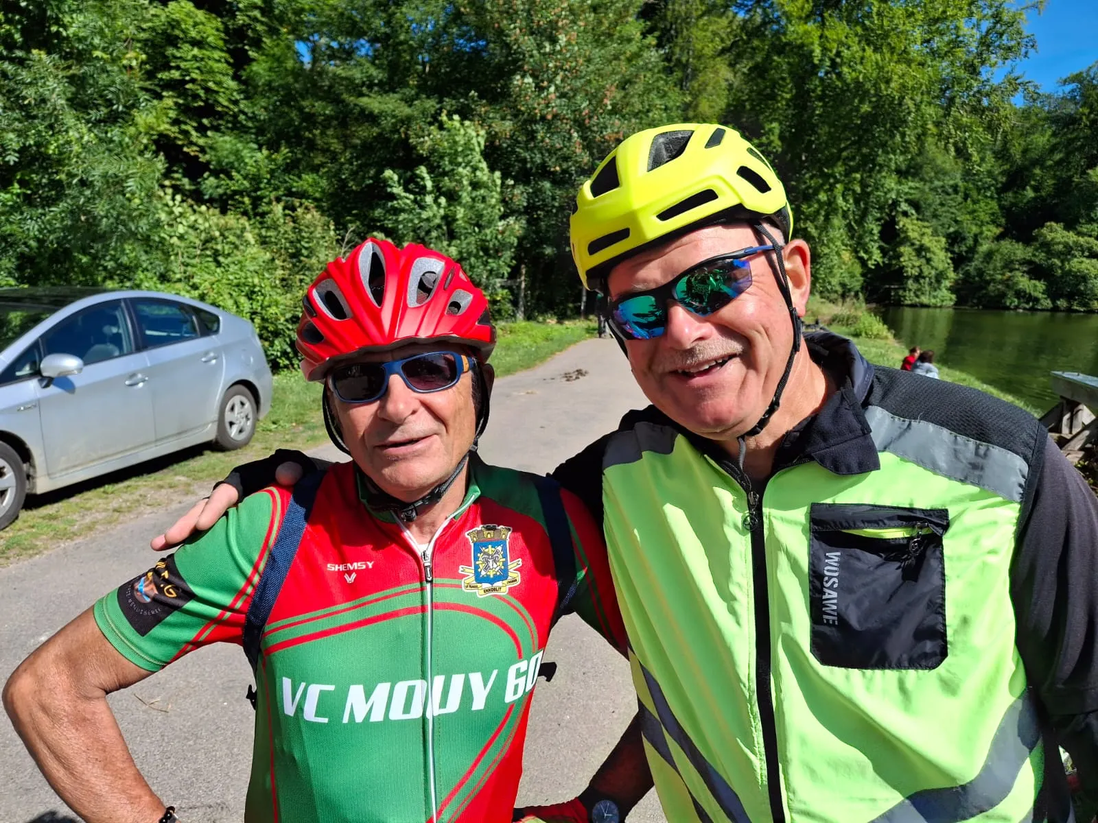 Deux membres du VC Mouy en maillot du club posant côte à côte au bord de l'eau lors de la rando de la Nonette