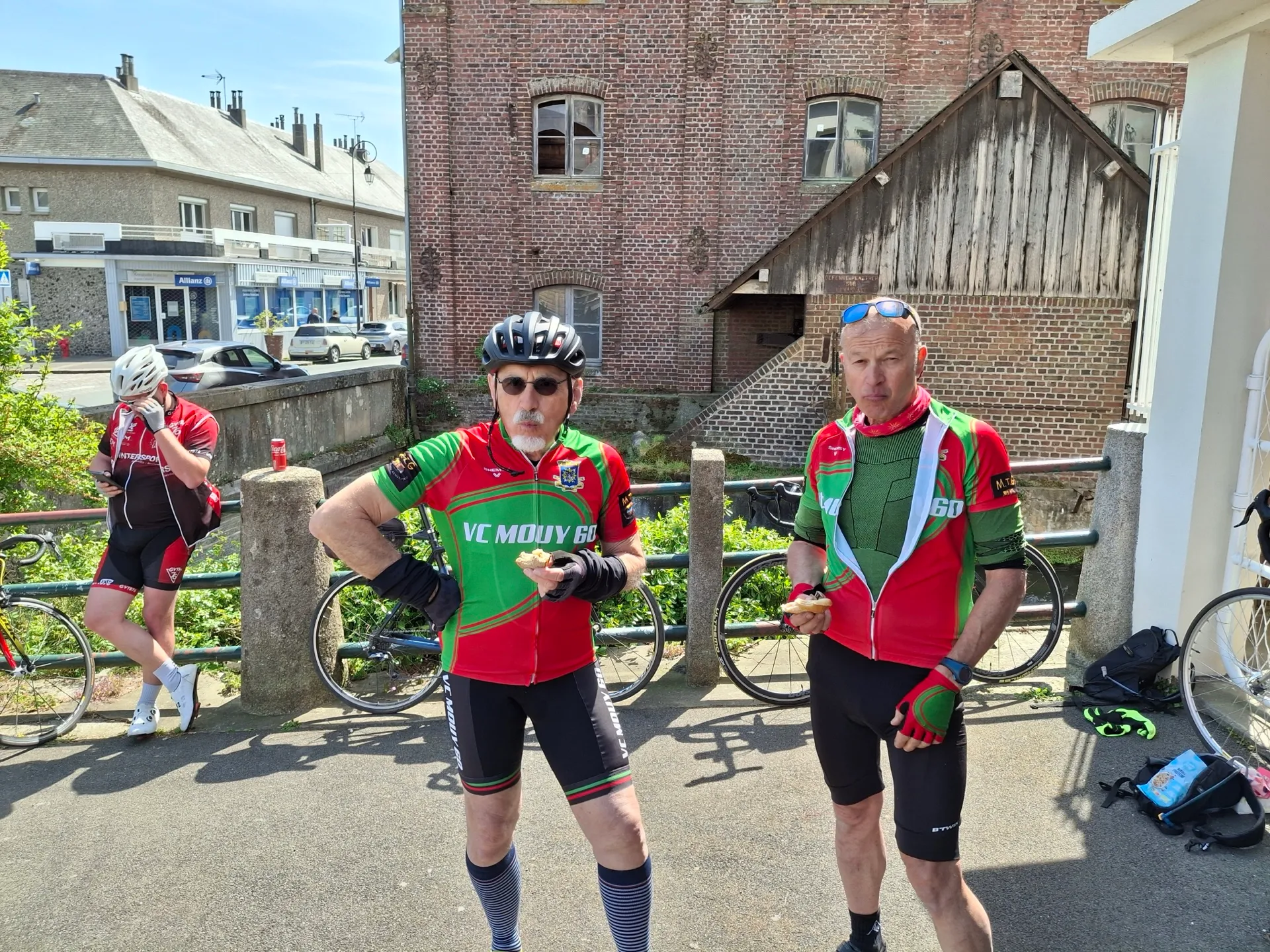 Deux cyclistes du VC Mouy en maillot vert et rouge devant un bâtiment de briques au Picardo Normand 2026