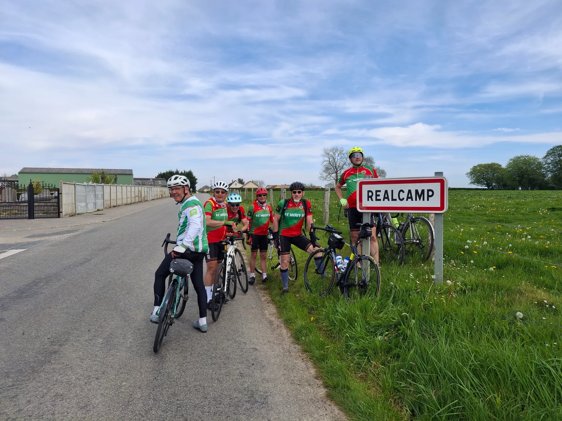 Groupe de cyclistes du VC Mouy au panneau Realcamp lors du Picardo Normand 2026