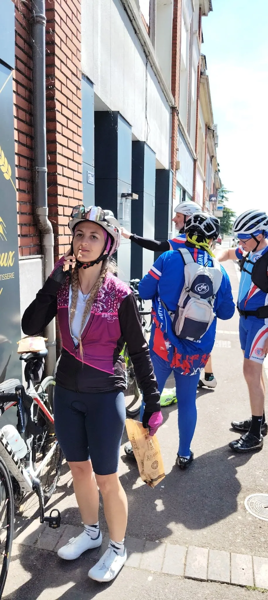 Cyclotouriste du Picardo Normand 2026 en maillot violet et noir devant une boulangerie