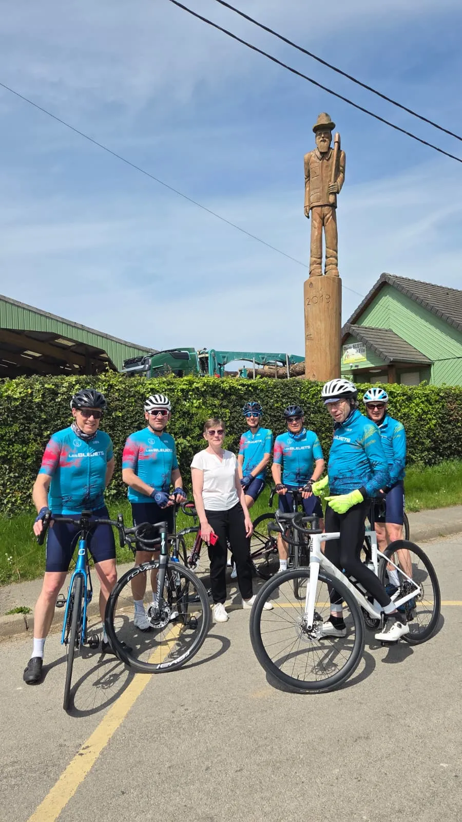 Groupe de cyclistes du Picardo Normand 2026 devant une statue de bois sculptée