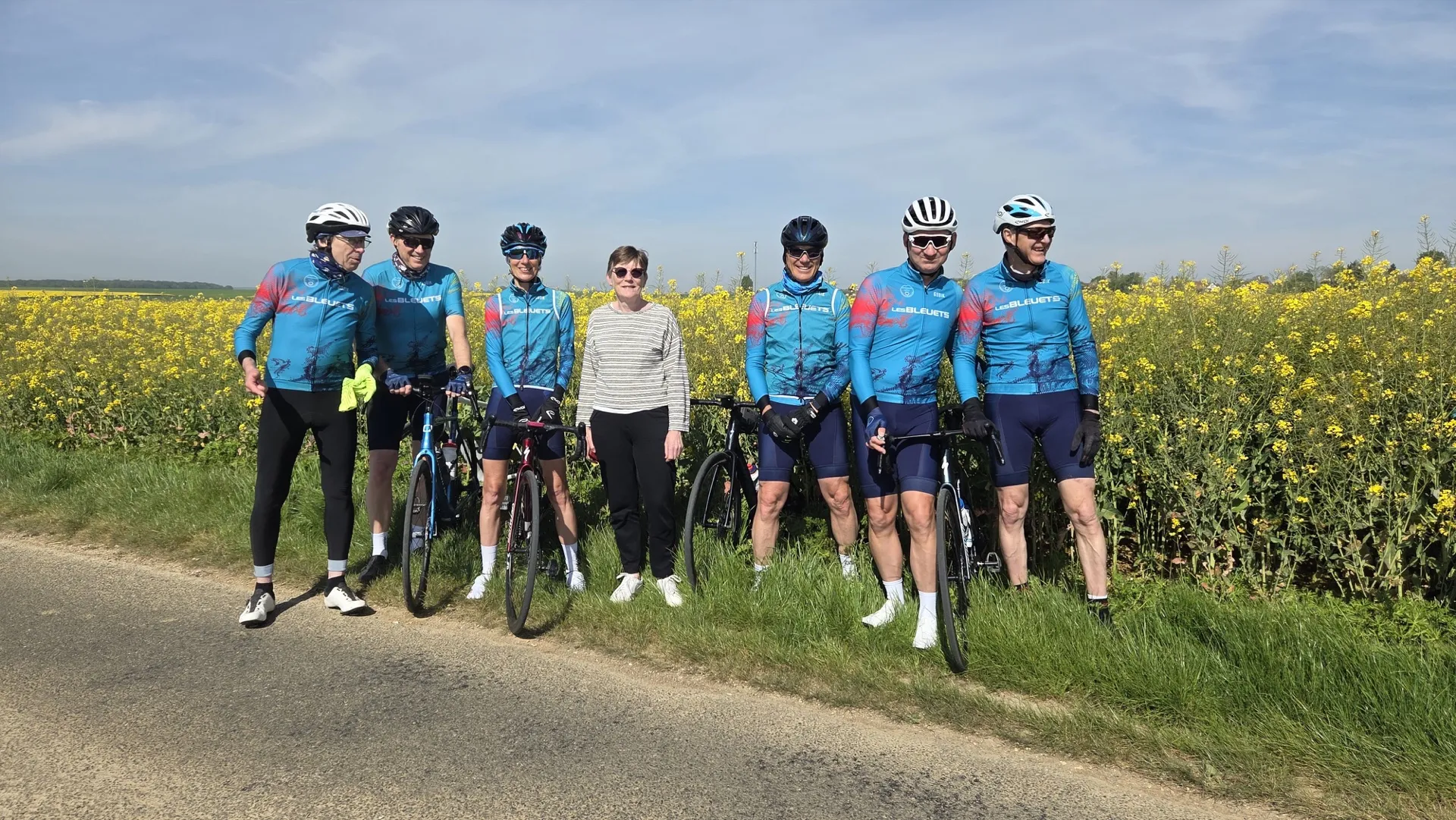 Groupe de cyclistes du Picardo Normand 2026 posant devant un champ de colza en floraison