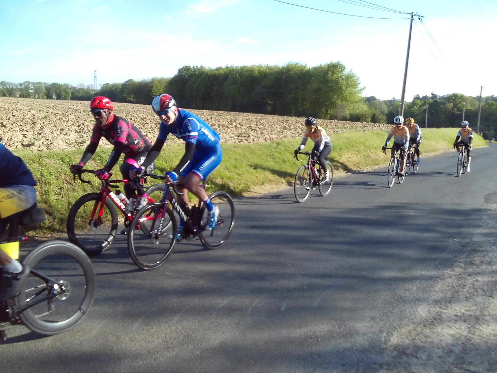 Peloton du Picardo Normand 2026 en mouvement sur la route entre champs et bois