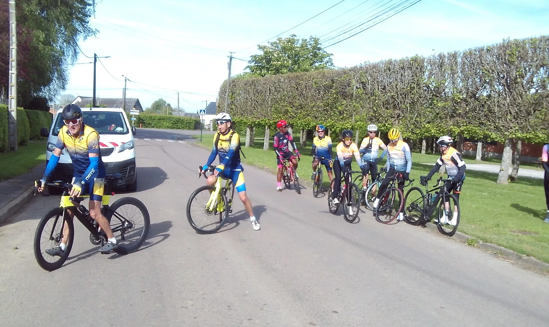 Cyclotouristes du Picardo Normand 2026 entourant un véhicule de soutien sur la route