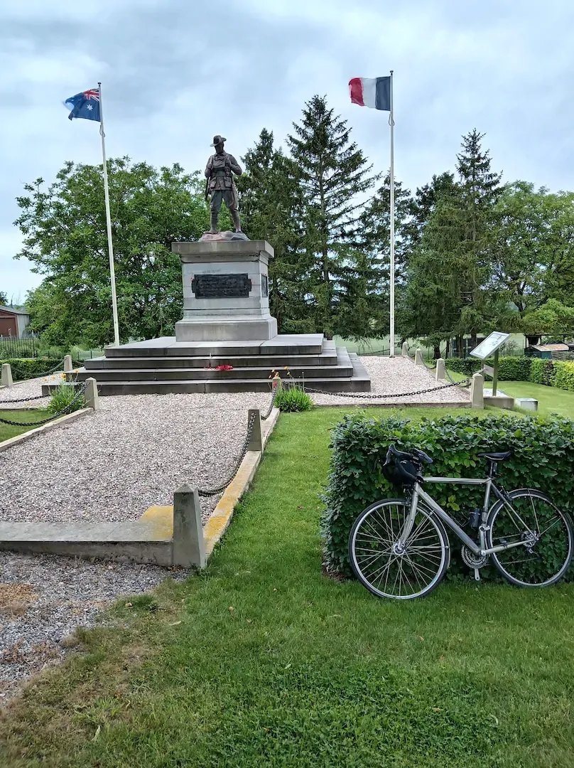 Monument commémoratif avec drapeaux et vélo sur les chemins de la Grande Guerre